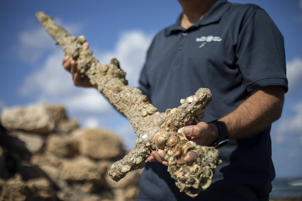 Jacob Sharvit, diretor da Unidade de Arqueologia Marinha da Autoridade de Antiguidades de Israel, segura espada de um metro de comprimento que foi encontrada no Mar Mediterrâneo e especialistas dizem remontar aos cruzados em foto de 19 de outubro de 2021 — Foto: Ariel Schalit/AP
